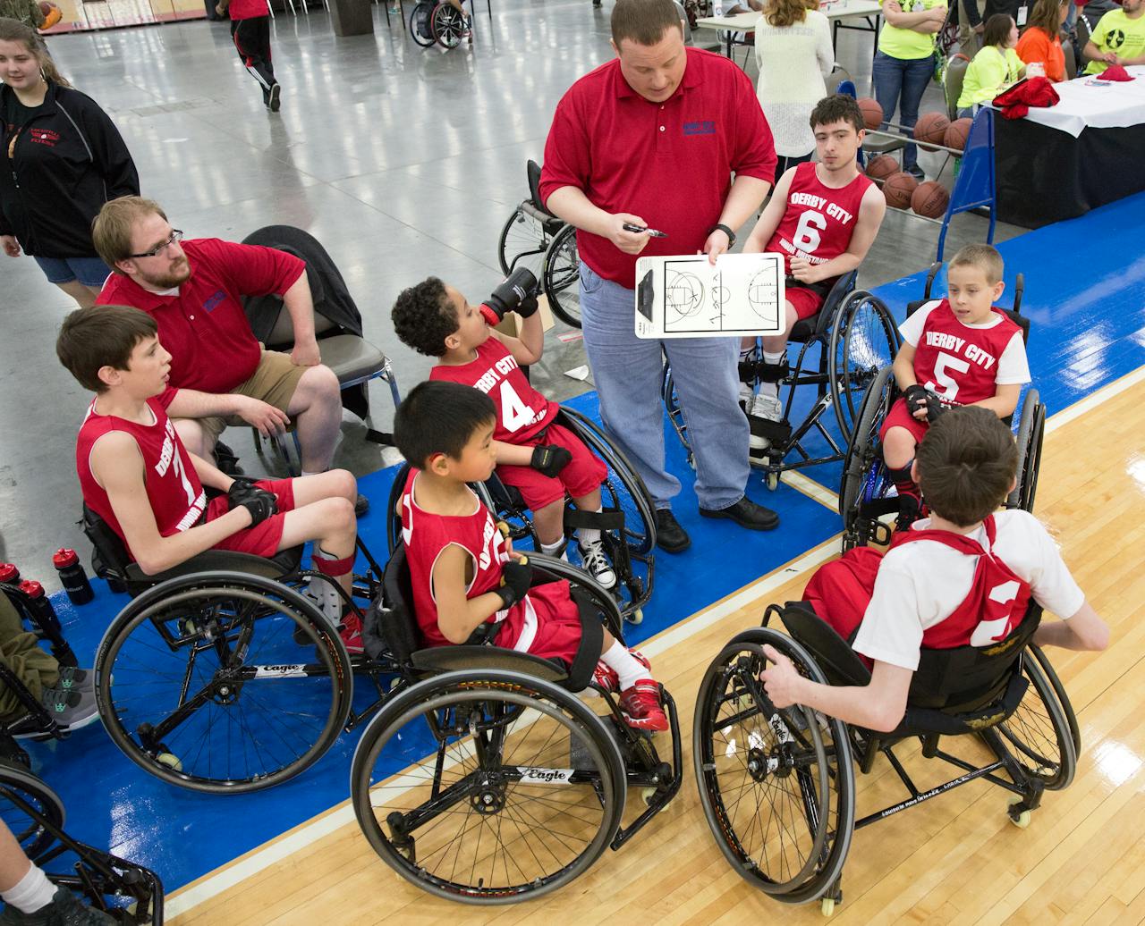 Service Young wheelchair basketball players and coach strategize during a game in Louisville.